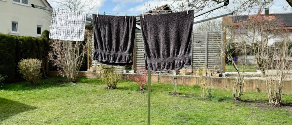 Dunkle und helle Handtücher hängen nebeneinander auf der Brabantia Lift-O-Matic 50 im Garten.