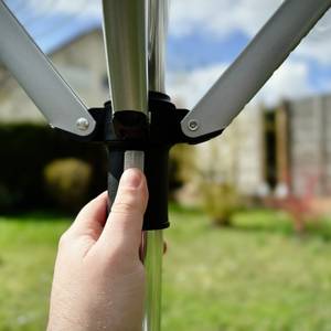 Eine Hand drückt das Gestell nach oben zum Öffnen der Spinne im Garten.
