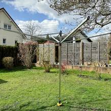 Die Brabantia Lift-O-Matic 50 steht vollständig geöffnet im Garten. Die Leinen sind gespannt und einsatzbereit.