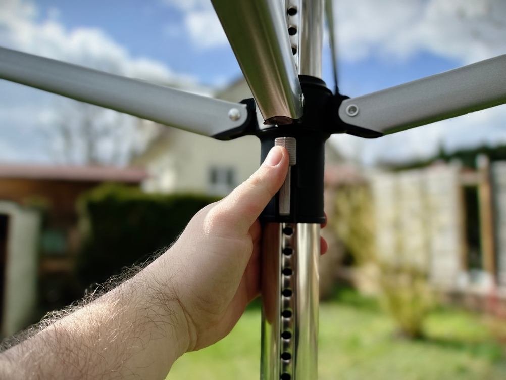 Eine Hand hält die zentrale Schiebeführung der Brabantia Lift-O-Matic 50 zur Höhenverstellung.