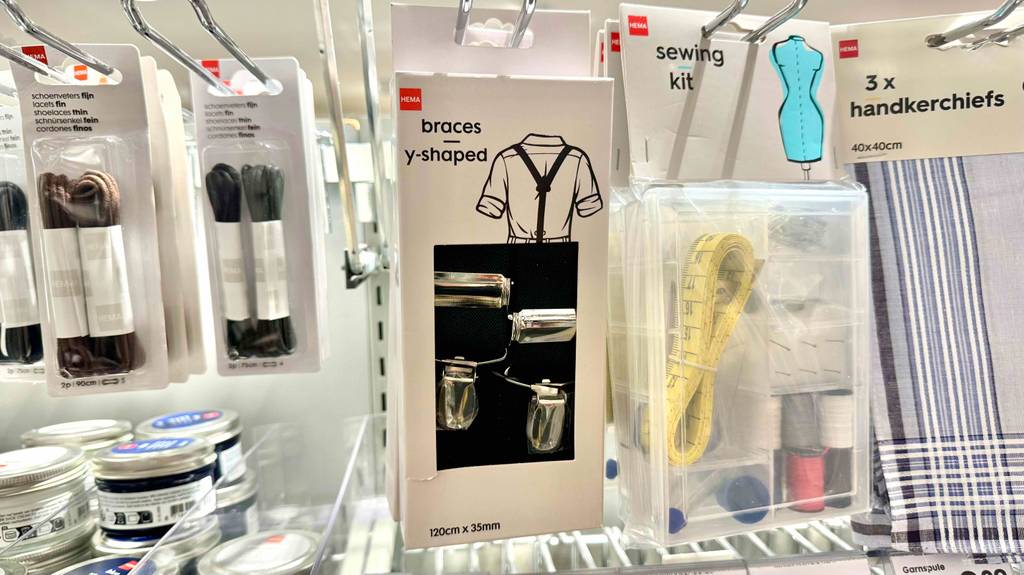 Hosenträger-Test: Mehrere Packungen mit schwarzen Hosenträgern hängen an einem Verkaufsstand mit nützlichen Haushaltsgegenständen.