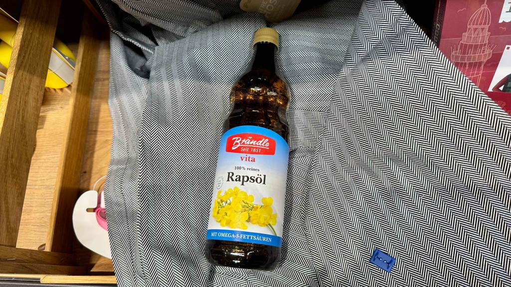 Im Test: Eine Flasche Rapsöl liegt auf einem dunklen Tuch.