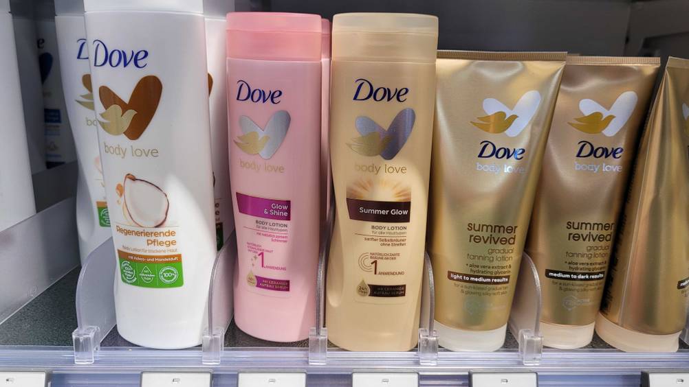 Eine Flasche der getesteten bräunenden Bodylotion neben anderen Produkten im Regal.