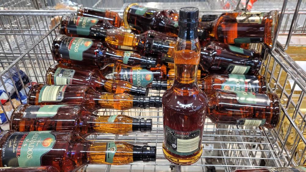 Rückseite einer Flasche Brandy im Test auf einem Gitter, im Hintergund mehrere andere Flaschen.