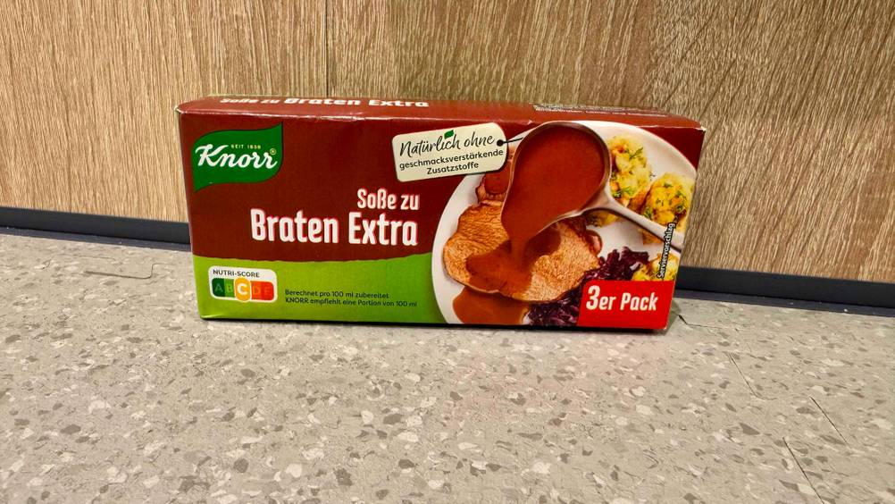 Bratensoße im Test: Eine Packung vor einem Holzregal auf dem Boden.
