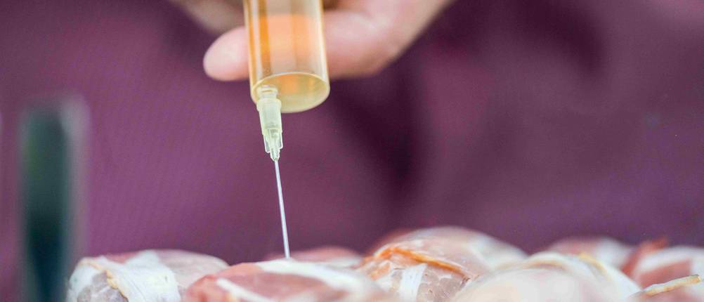 Bratenspritze-Test: Eine Bratenspritze aus Kunststoff mit Edelstahlnadel wird in ein Fleischstück gestochen