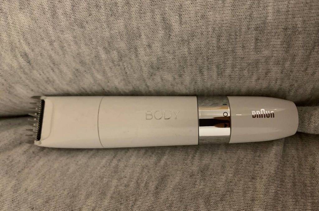 Weißer batteriebetriebener Braun Körperrasierer im Test liegt ohne direkte Klingen auf einer hell melierten Unterlage.