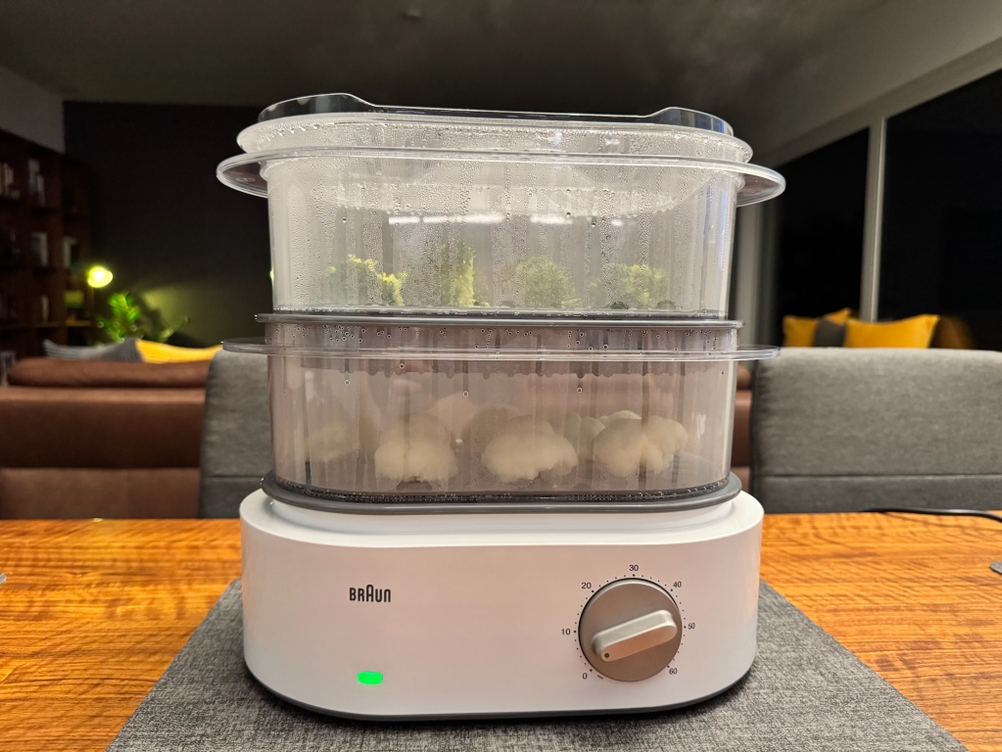 Der Braun Dampfgarer Identity Collection ist angeschaltet, eine grüne Leuchte ist an und die Behälter mit Blumenkohl und Brokkoli sind beschlagen.