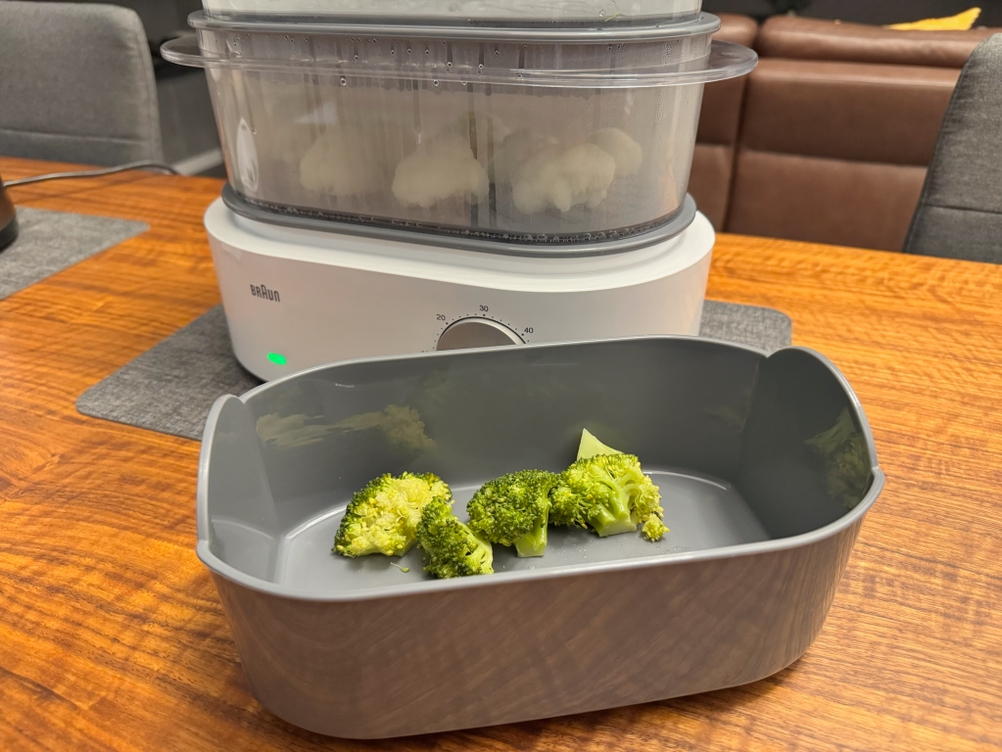 Fertiger Brokkoli liegt in einer Schale vor dem Braun Dampfgarer Identity Collection.