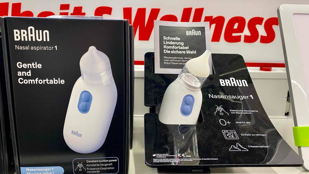 Elektrischer Nasensauger getestet: Ein Gerät in einem Ständer mit Informationen, neben der Originalverpackung in einem Verkaufsregal.