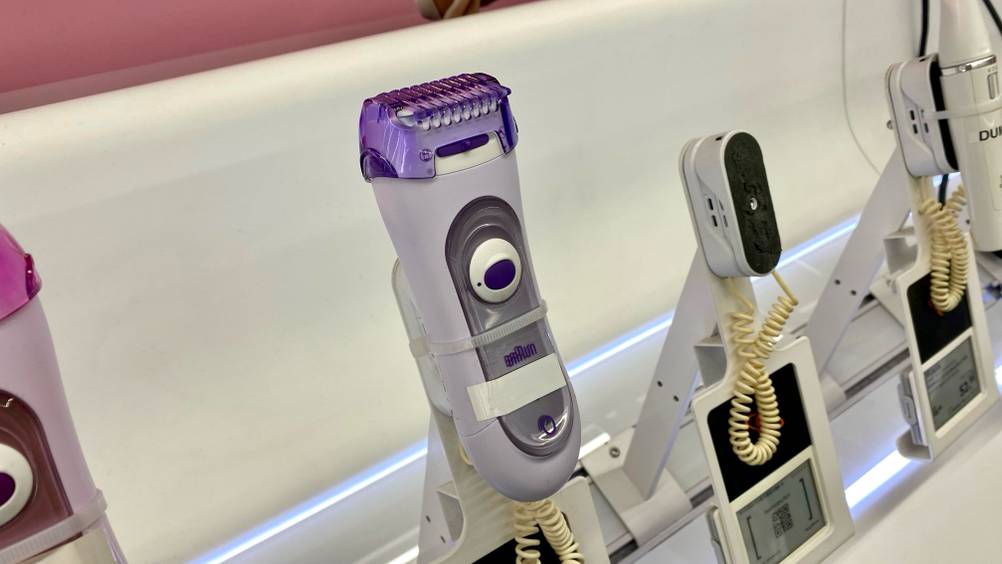 Im Test: Ein Braun-Haarentferner auf einem hellen Sockel neben anderen Geräten in einer Verkaufsausstellung.