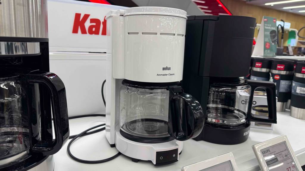 Eine Kaffeemaschine in weiß steht zum Testen zwischen anderen Geräten.