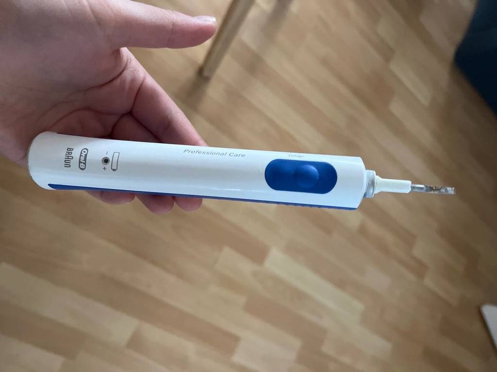 Braun Oral-B Munddusche im Test: Hand hält das weiß-blaue Modell ohne Aufsatz.