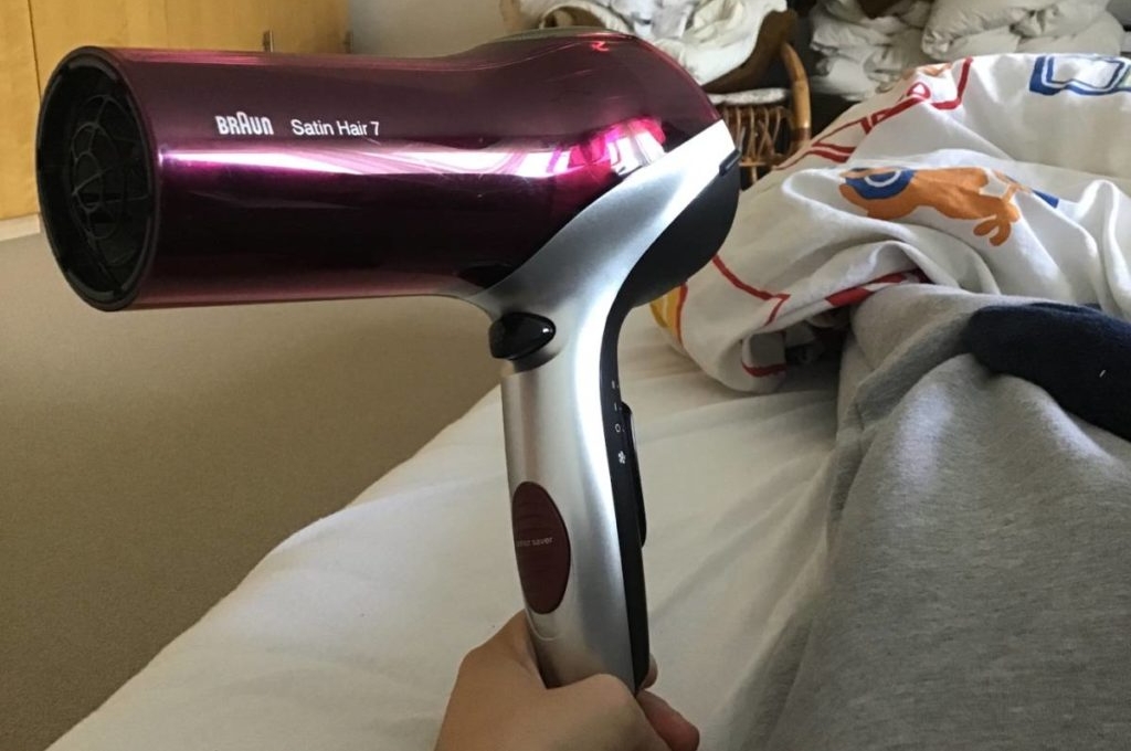 Hand hält einen Ionen-Haartrockner in Bordeaux-Silber-Design.