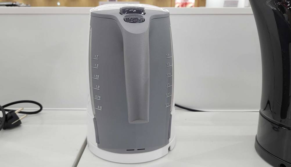 Ein getesteter Braun-Wasserkocher von hinten mit Griff und Scalen auf einem weißen Regal.
