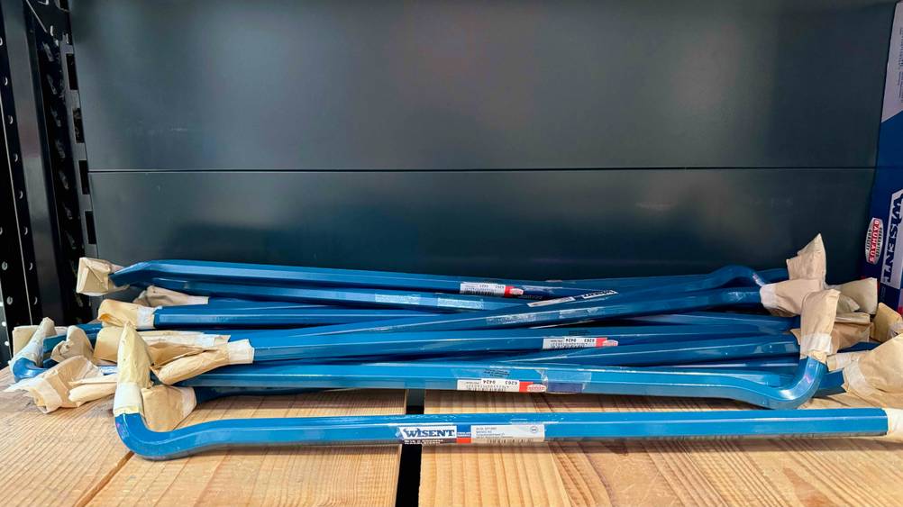 Getestet: Mehrere Brecheisen liegen auf einem Holzregal vor einer dunklen Wand.