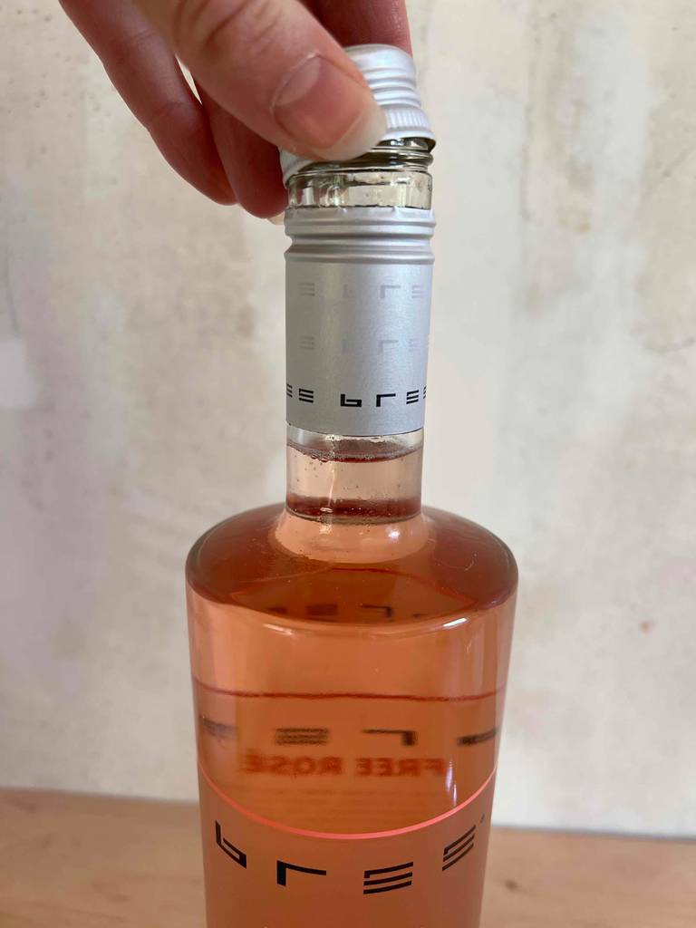 Alkoholfreier Wein getestet: Hand hält den Schraubverschluss einer Flasche an den Flaschenhals.