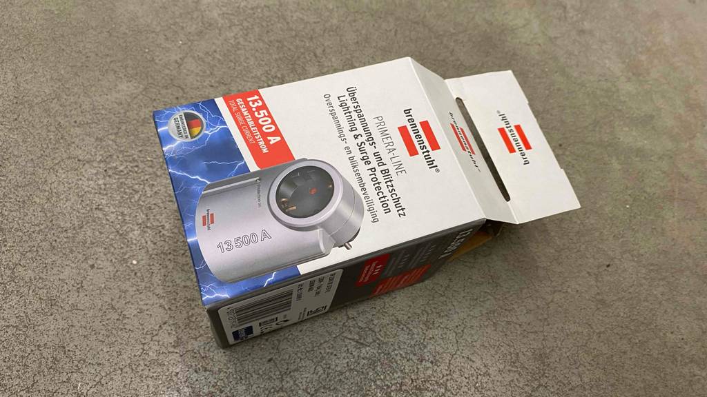 Überspannungsschutz im Test: Eine Verpackung von einem metallfarbenem Überspannungs- und Blitzschutz von Brennenstuhl liegt auf einer grauen Oberfläche.
