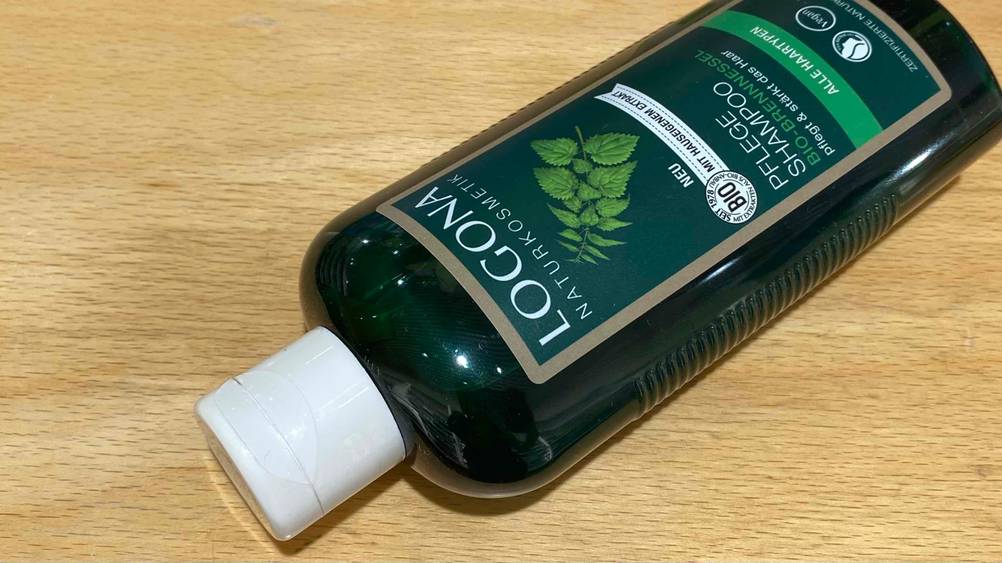 Eine Flasche des getesteten Brennnessel-Shampoos mit Fokus auf den Verschluss auf einer Holzfläche.