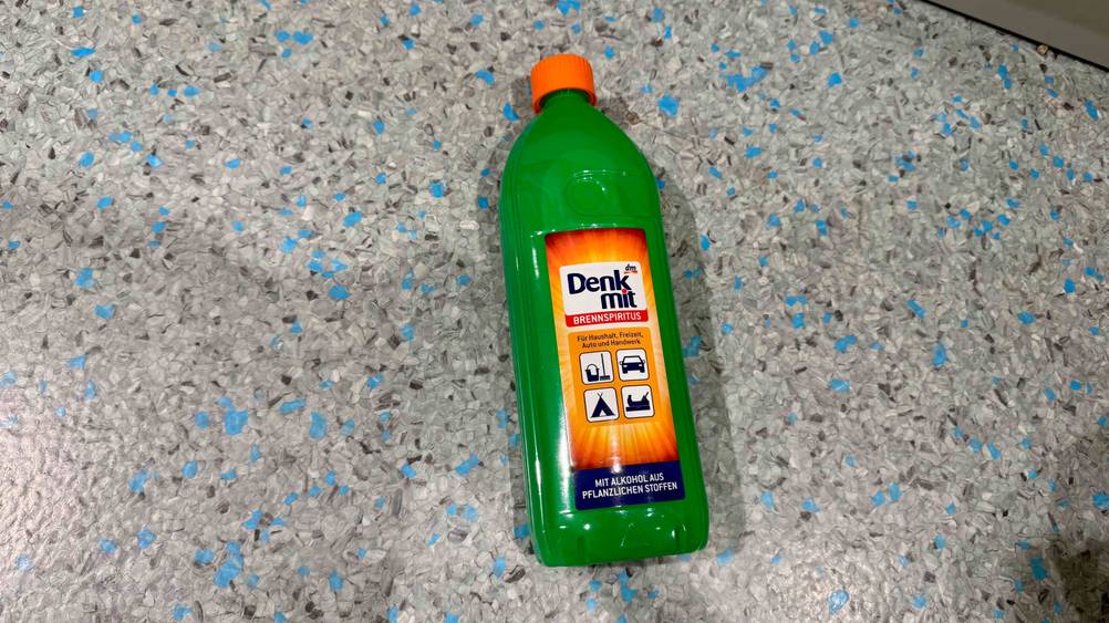 Auf dem Boden liegt eine Flasche des getesteten Brennspiritus.