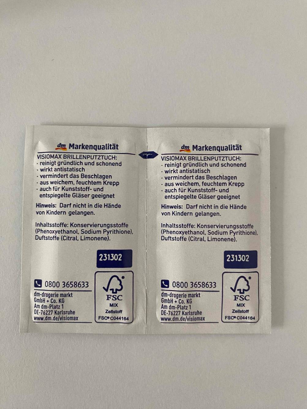 Rückseite zweier einzeln verpackter Brillenputztücher im Test auf einer hellen Fläche.