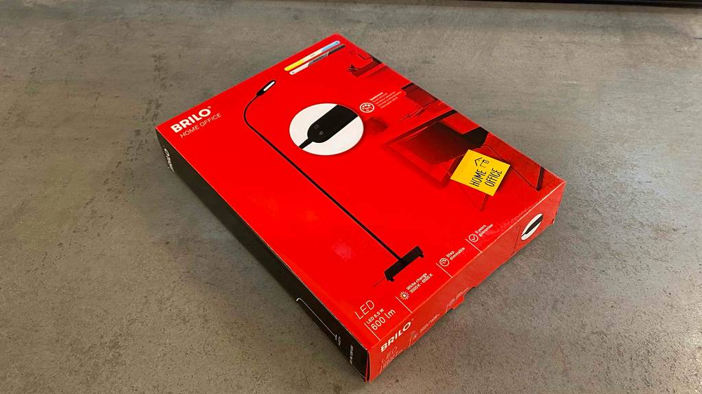 Im Test: Eine originalverpackte Stehlampe fürs Büro liegt schräg auf einem Steinboden.