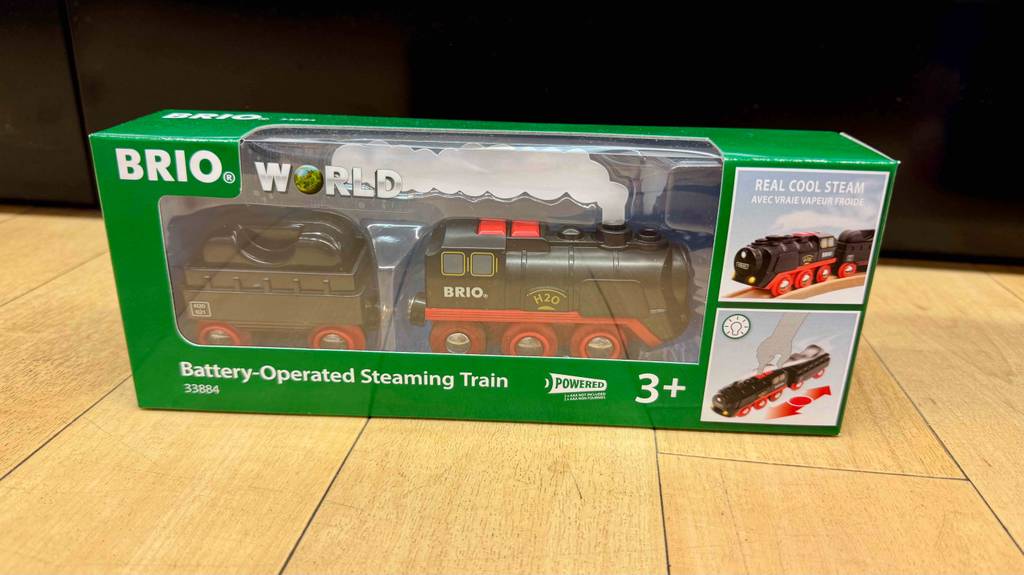 Eine getestete Brio-Eisenbahn steht in Originalverpackung auf einem Holzboden.