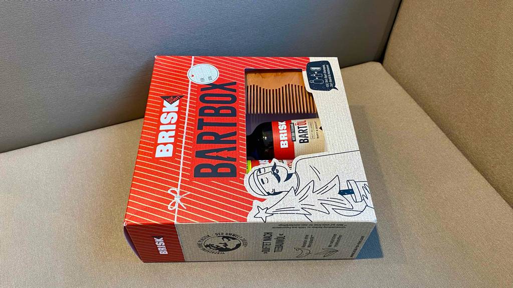 Ein getestetes Bartpflege-Set von Brisk Bartbox liegt in seiner Verpackung auf einer beigefarbenen Fläche.