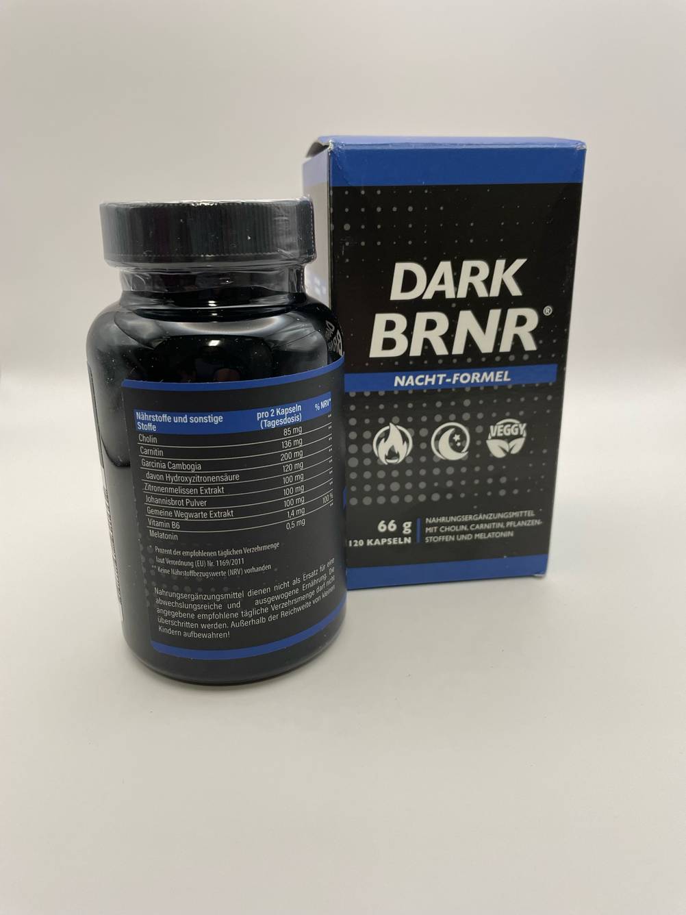 Ein Glas getestete Fatburner steht mit der Rückseite nach vorn neben dem Originalkarton.