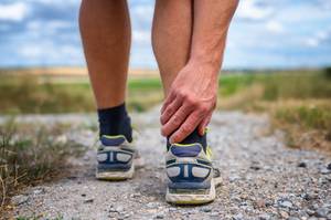 Brooks-Laufschuhe-Damen-Test: Ein Mann greift sich mit der Hand an den rechten Fuß.