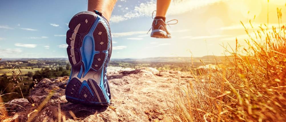 Brooks-Laufschuhe-Herren-Test: Jemand läuft auf einem unebenen Weg, wobei die Sohle eines Schuhs ersichtlich ist.