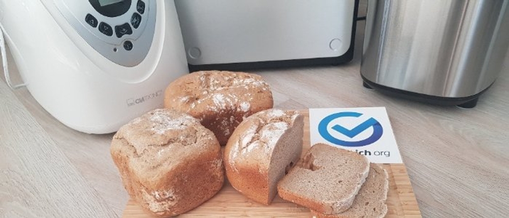 Brotbackautomaten im Hintergrund stehend, mit einem kleinen Brot im Vordergrund.