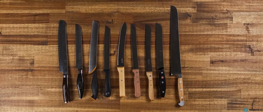 Brotmesser im Test: diverse Brotmesser liegen auf einer Holz-Arbeitsplatte.