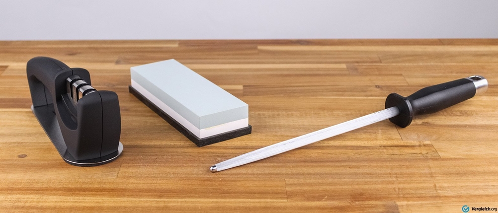 Brotmesser im Test: Wetzstahl, Messerschärfer und Schärfstein auf einer Holz-Arbeitsfläche.