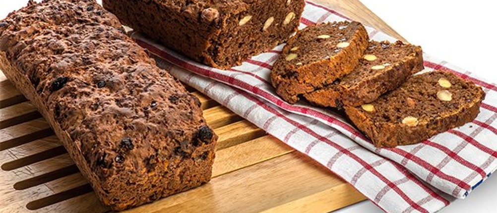 Brotscheiben und ein ganzes Brot liegen zusammen mit einem Geschirrtuch auf einem Brotschneidebrett.