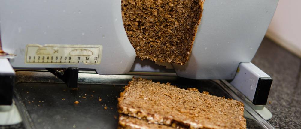 In einer getesteten manuellen Brotschneidemaschine wird Körnerbrot geschnitten.