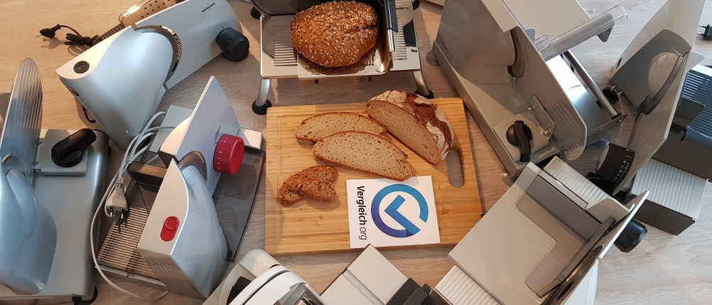 Brotschneidemaschinen stehen im Kreis um ein Brett mit Brot herum