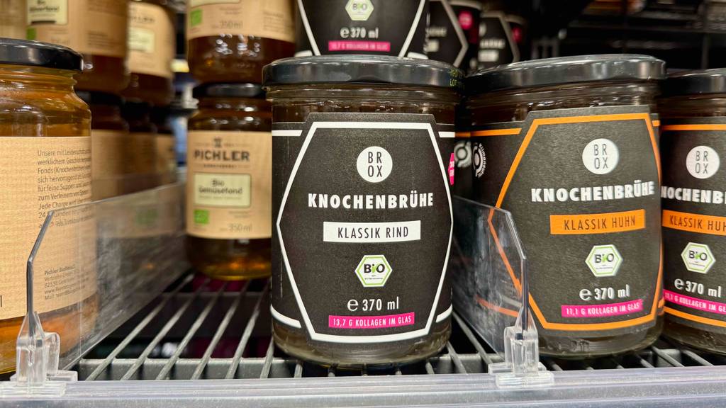 Ein 370-ml-Glas mit Schraubverschluss, das getestete Knochenbrühe enthält, befindet sich auf einem Verkaufsregal neben weiteren Brühe-Gläsern.