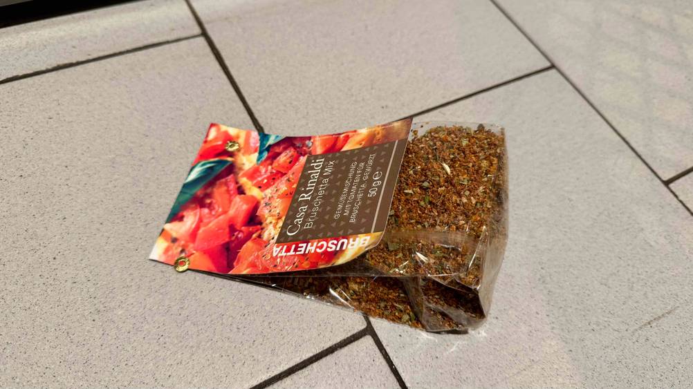 Getestet: Eine Packung Bruschetta-Gewürz liegt horizontal auf einer Fließenfläche.