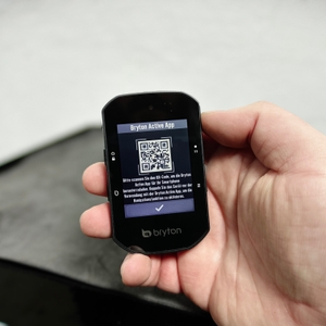 Ein Bryton Rider S500 wird aus nächster Nähe in der Hand gehalten. Auf dem Display ist ein QR-Code zur Bryton Active App zu sehen.