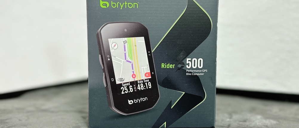 Die Verpackung des Bryton Rider S500 zeigt das Gerät mit aktivem Navigationsdisplay. Die Box steht auf einem grauen Untergrund vor weißer Wand.