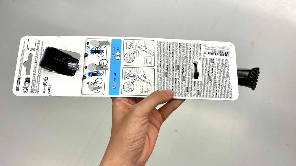 Hand zeigt Rückseite einer Fahrradständerverpackung mit Anleitung