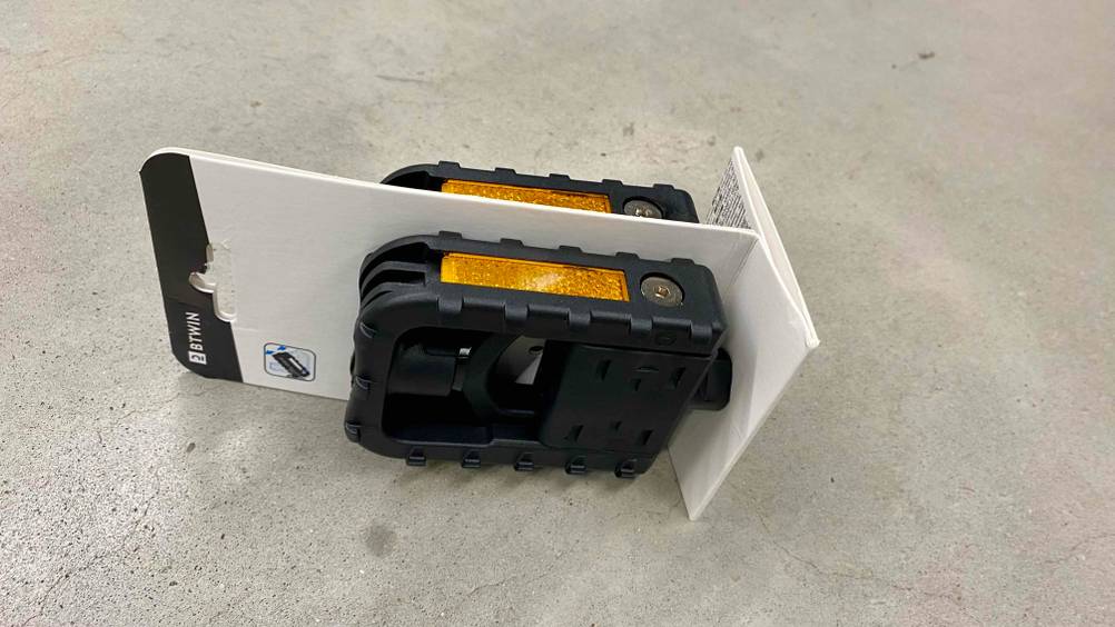 Ein Paar getestete Klapppedale in Verpackung auf einem Betonboden liegend.