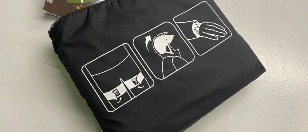 Getesteter Regenponcho: Verpackter Regenponcho in Giftgrün und Schwarz liegt auf hellem Untergrund.