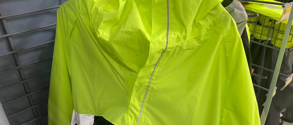 Regenponcho im Test: Regenponcho in giftgrüner Signalfarbe hängt an einem Verkaufsstand.