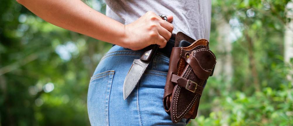Buck-Messer im Test: Frau im Wald mit Leder-Holster am Gürtel und Messer in der Hand