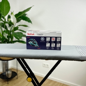 Die Rückseite der Verpackung des Tefal FV9844 Dampfbügeleisens zeigt Produktvorteile und technische Details. Die Verpackung ist weiß und blau mit roten Markierungen.