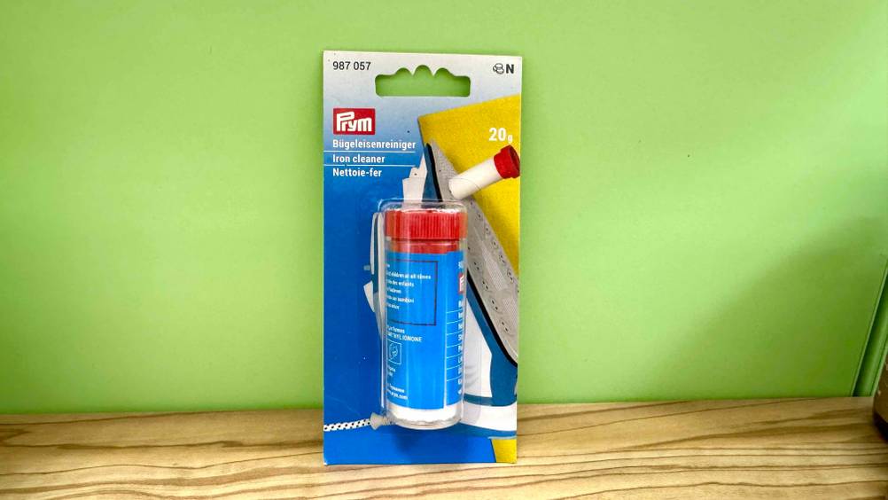 Vor einer grünen Wand steht der verpackte Bügeleisenreiniger im Test.