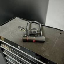 Das Bügelschloss von Trelock liegt ausgepackt mit Zubehör auf einem Rollwagen.