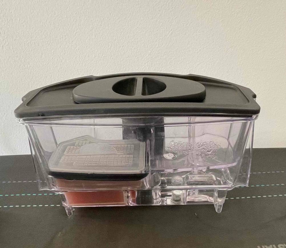 Bügelsystem getestet: Der Wasserbehälter auf einer dunklen Fläche vor einer hellen Wand.
